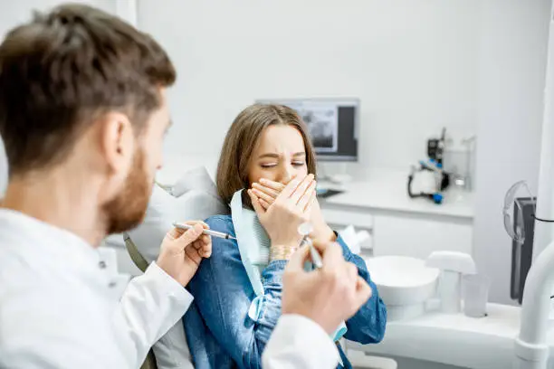 Woman with a frightened facial expression during a stomatological procedure with male doctor in the dental office
