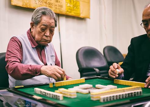 Japanese senior citizens playing mahjong in a parlor.
