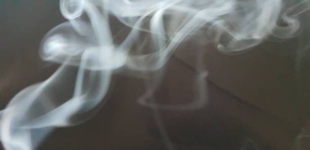 istock Wispy twirls of incense smoke against dark background with copy space 1089097024