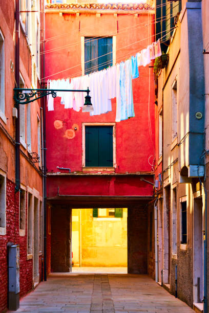 backyard at Venice, red and purple clothes drying on clothes-line, woman hanging a shirt from her window