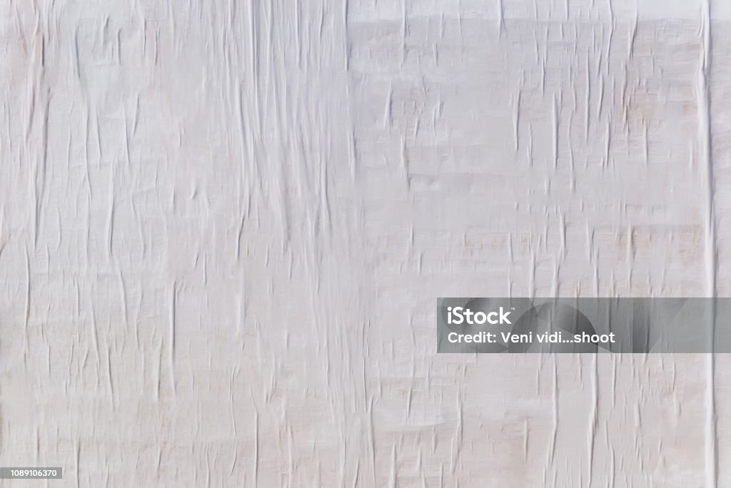 Texture of wet white folded paper on an outdoor poster wall, crumpled paper background Texture of wet white folded paper on an outdoor poster wall, crumpled paper background. Paper Stock Photo