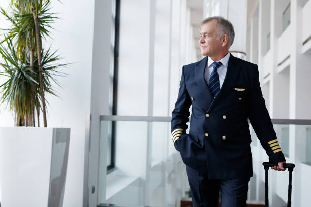 istock Experienced senior pilot pulling his luggage in the airport terminal 1089106852