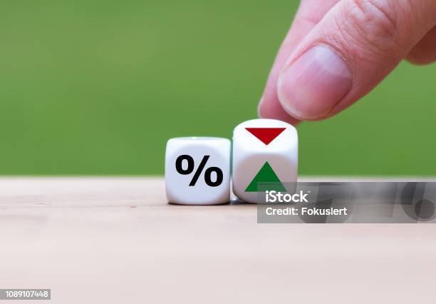 Hand Is Turning A Dice And Changes The Direction Of An Arrow Symbolizing That The Interest Rates Are Going Down Stock Photo - Download Image Now