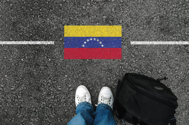 a man with a shoes and flag of Venezuela a man with a shoes and backpack is standing on asphalt next to flag of Venezuela and border venezuela stock pictures, royalty-free photos & images