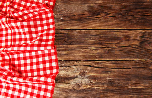 istock Red checkered tablecloth lies on a brown wooden table 1089129112