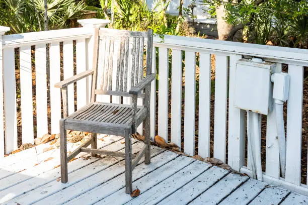 Closeup of empty wooden chair, nobody in patio outdoor garden backyard porch deck of home, wood with plants, fence in tropical Florida
