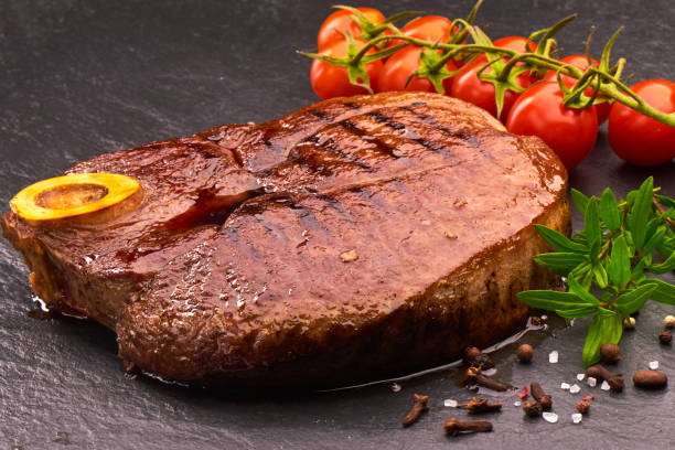 istock Grilled beef steak with cherry tomatoes and spices on black stone board 1089131006