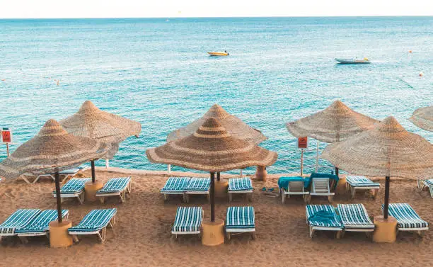 Beautiful sunny beach and parasols on the coast of the Red Sea in the city of Sharm El Sheikh, Egypt. Tourist recreation area on the Sinai Peninsula