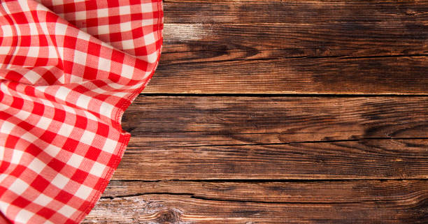 istock Red checkered tablecloth lies on a brown wooden table 1089139232