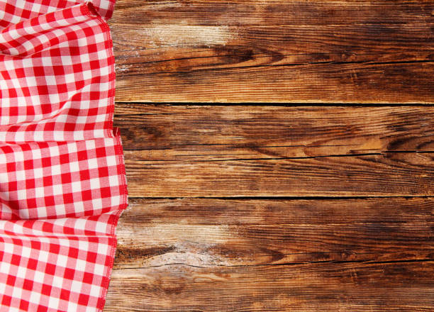 istock Red checkered tablecloth lies on a brown wooden table 1089146366
