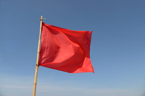 istock red flag swaying in the wind on a blue sky background 1089166546