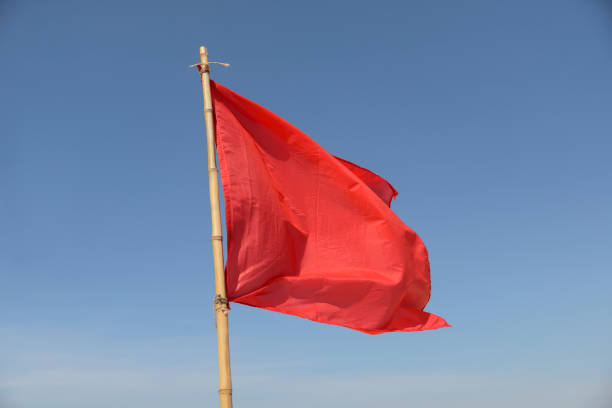 istock red flag swaying in the wind on a blue sky background 1089166570