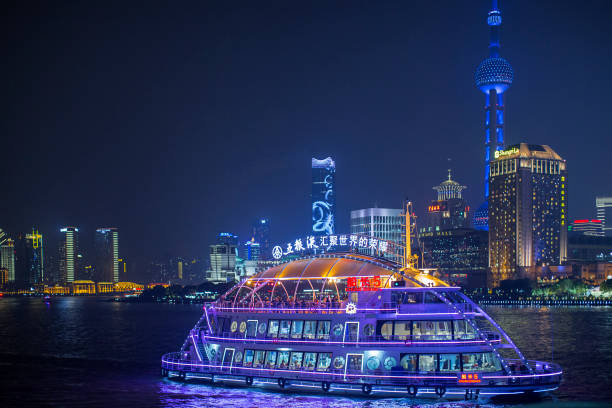 Shanghai, China - October 15, 2018:  A tour boat cruises at the Huangpu River of Shanghai withbeautiful cityscape night view at the background.