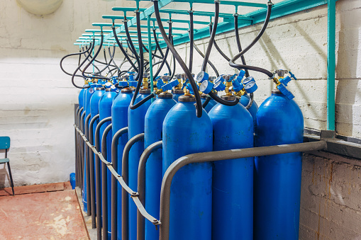 Bundle of blue gas cylinders with pressure gauges.