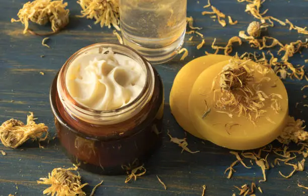 Facial cream of calendula and beeswax, on a blue wooden background
