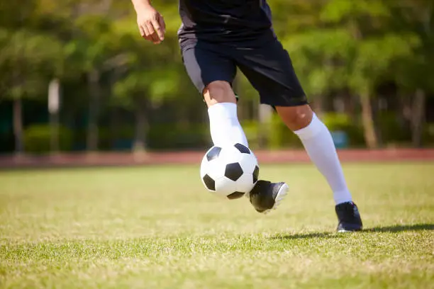 close-up shot of feet of asian soccer player handling the ball on football field.