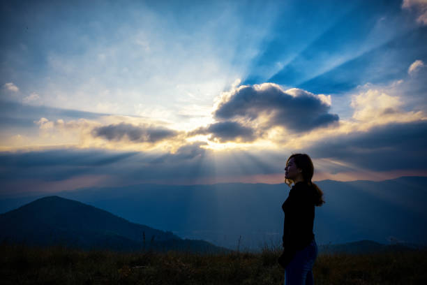 A beautiful asian woman standing and watching sunset with mountains view