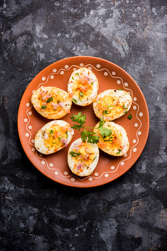 Fried hot boiled egg masala is a popular healthy breakfast or starter menu from India. With onion, coriander, black pepper, tomato and salt sprinkled over half of eggs