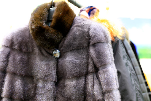Luxury fur coats hanging on rack, various colors of mink, fox and sheep fur for sale at the market