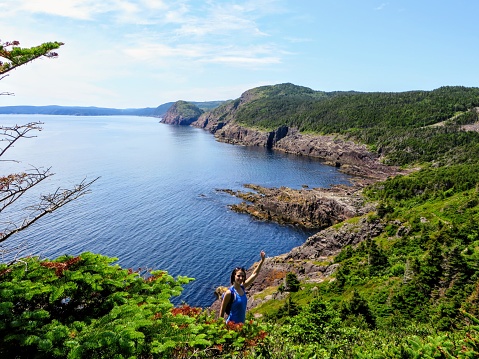 A hiker fist pumping while hiking the east coast trail off the coast of Newfoundland and Labrador, Canada.  This section of the hike is outside of St. John's and is called the Sugarloaf trail.