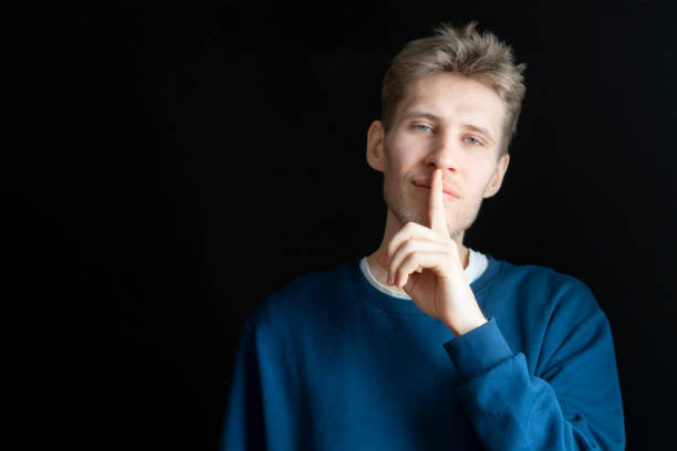 istock handsome male holding his finger on lips in total silent 1089241800