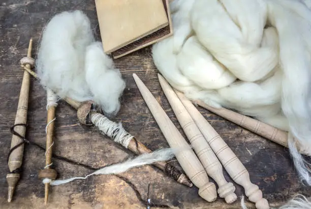 Tools for spinning wool and white sheep's wool.  Rural environment, rustic life.