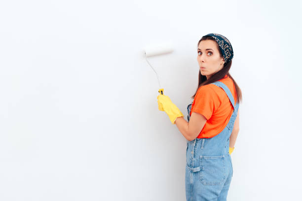 istock Woman Painting White Wall with Paint Roller 1089261758