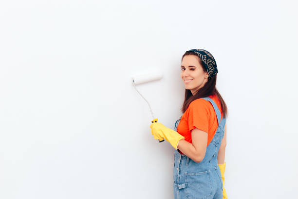 istock Woman Painting White Wall with Paint Roller 1089261760