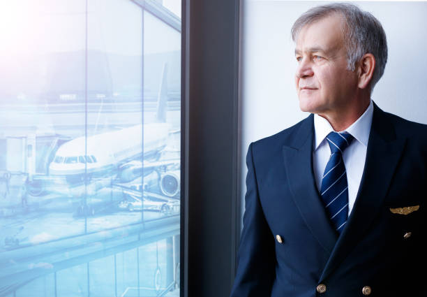 experienced senior pilot waiting at the airport lobby for flight - cabin crew pilot airport walking imagens e fotografias de stock