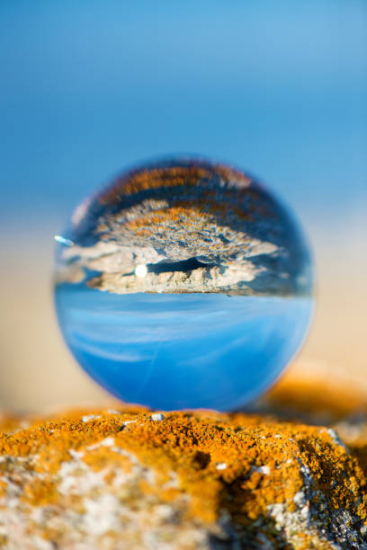 istock Upside down seascape with blue sky and overgrown with moss rocks - reflection in a lens ball - selective focus, space for text 1089275302