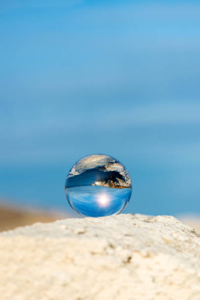 istock Upside down seascape with blue sky and overgrown with moss rocks - reflection in a lens ball - selective focus, space for text 1089275322