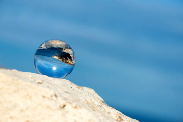 istock Upside down seascape with blue sky and overgrown with moss rocks - reflection in a lens ball - selective focus, space for text 1089275328