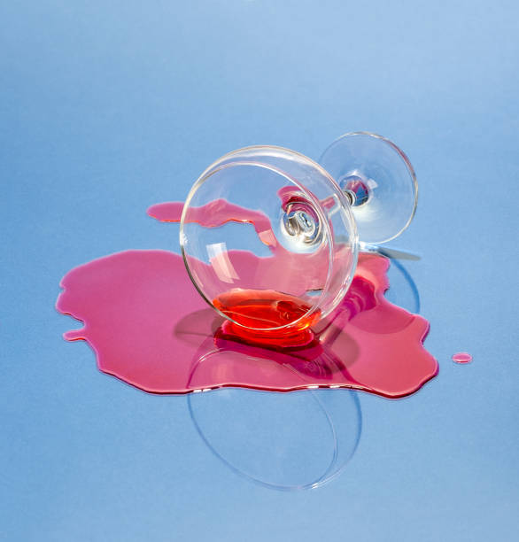 A glass and spilled liquor on a light blue background. Art photo. stock photo
