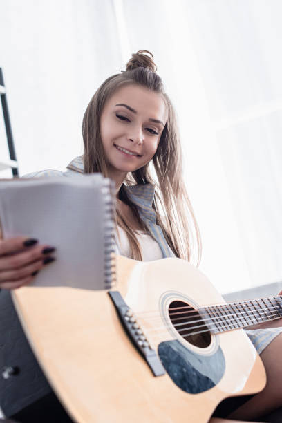 istock smiling musician holding notebook acoustic guitar at home 1089282152