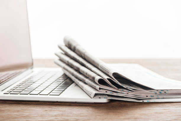 istock laptop and stack of newspapers on wooden tabletop 1089289406