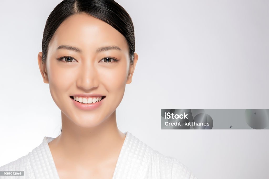Beautiful smiling woman with clean skin Beautiful smiling woman with clean skin, natural make-up, and white teeth on white background Asian and Indian Ethnicities Stock Photo