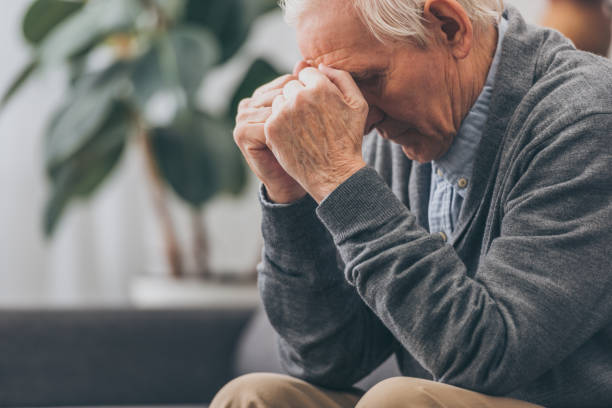 istock selective focus of upset retired man holding head while sitting on sofa 1089296752