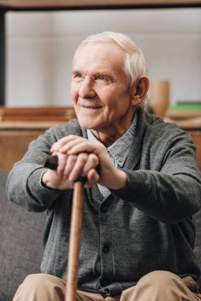 istock cheerful pensioner smiling and holding walking stick at home 1089296834