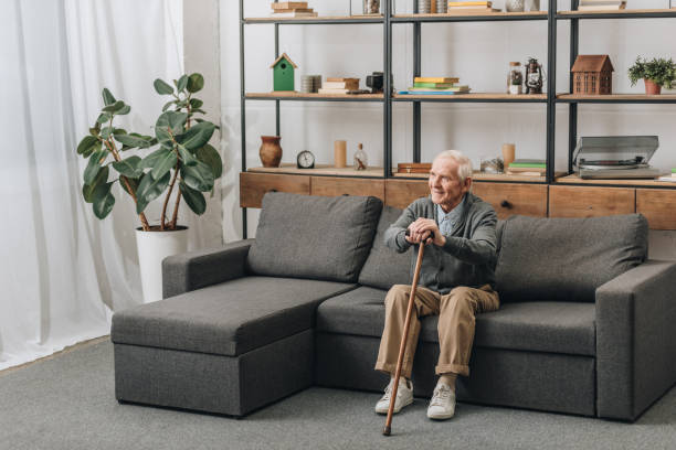 istock happy senior man smiling and holding walking cane while sitting on sofa 1089296838