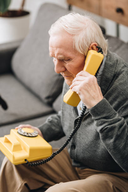 istock senior man talking on retro phone at home 1089300388