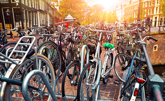 Amsterdam, Netherlands. Cycling parking along streets at channels. Sunset evening with sunshine. Bicycles is most popular transport type in Amsterdam.