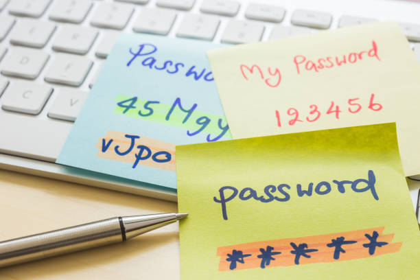 Online password management with keyborard, notes, pen. Silver pen pointing at handwriting passwords with highlight colors written on paper notes at modern white keyboard with office table on background. Data privacy management and cyber security concepts. password photos stock pictures, royalty-free photos & images
