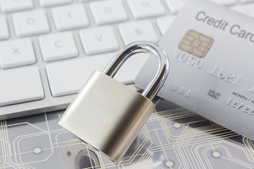 Metal padlock with gray credit card,  white keyboard and electronic circuits on background. Online shopping, data encryption, cyber security and financial transaction concepts.