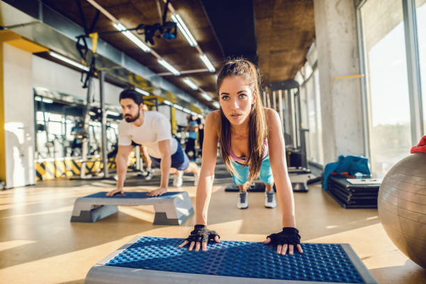 two caucasian focused friends doing planks on steppers in a gym. selective focus on woman. - secrecy instructor exercising individuality imagens e fotografias de stock
