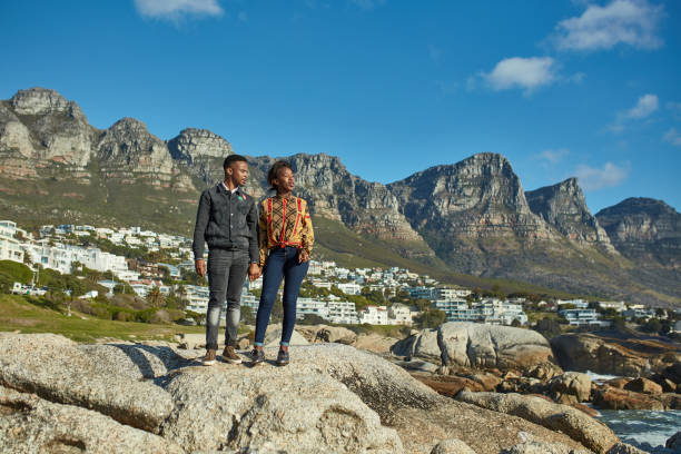 istock Young couple standing on rock against mountains 1089321946