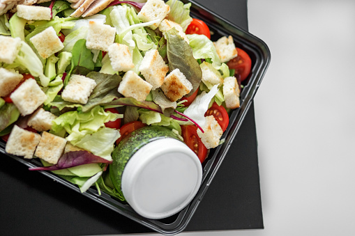 Salad with vegetables and chicken and pesto sauce in lunch box. The concept of food and food delivery.