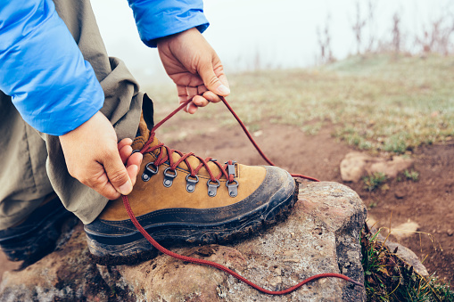 hiker tying shoelace on foggy highland mountain