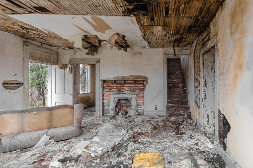 Interior of abandoned house falling apart with debris covering floor