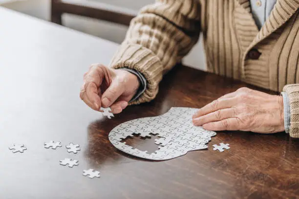 Photo of cropped view of senior man playing with puzzles