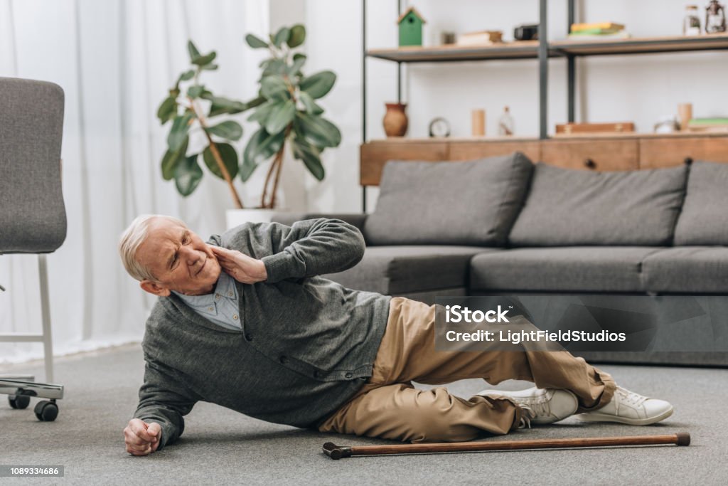 old men falled down on floor and touching neck Falling Stock Photo